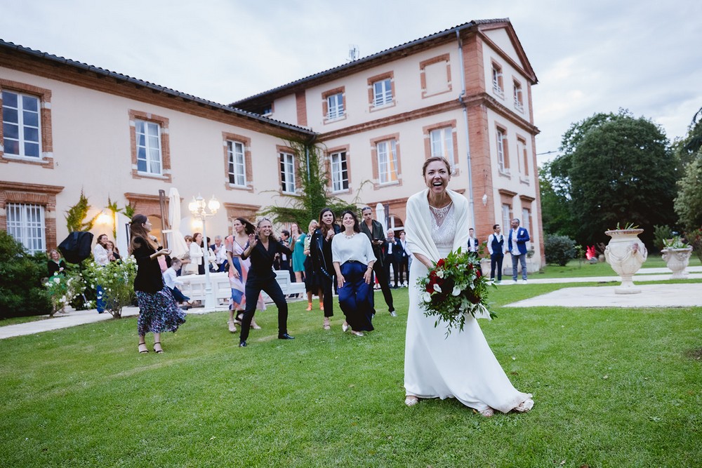 Mariée qui jette son bouquet de fleurs lors de son mariage en Haute-Garonne